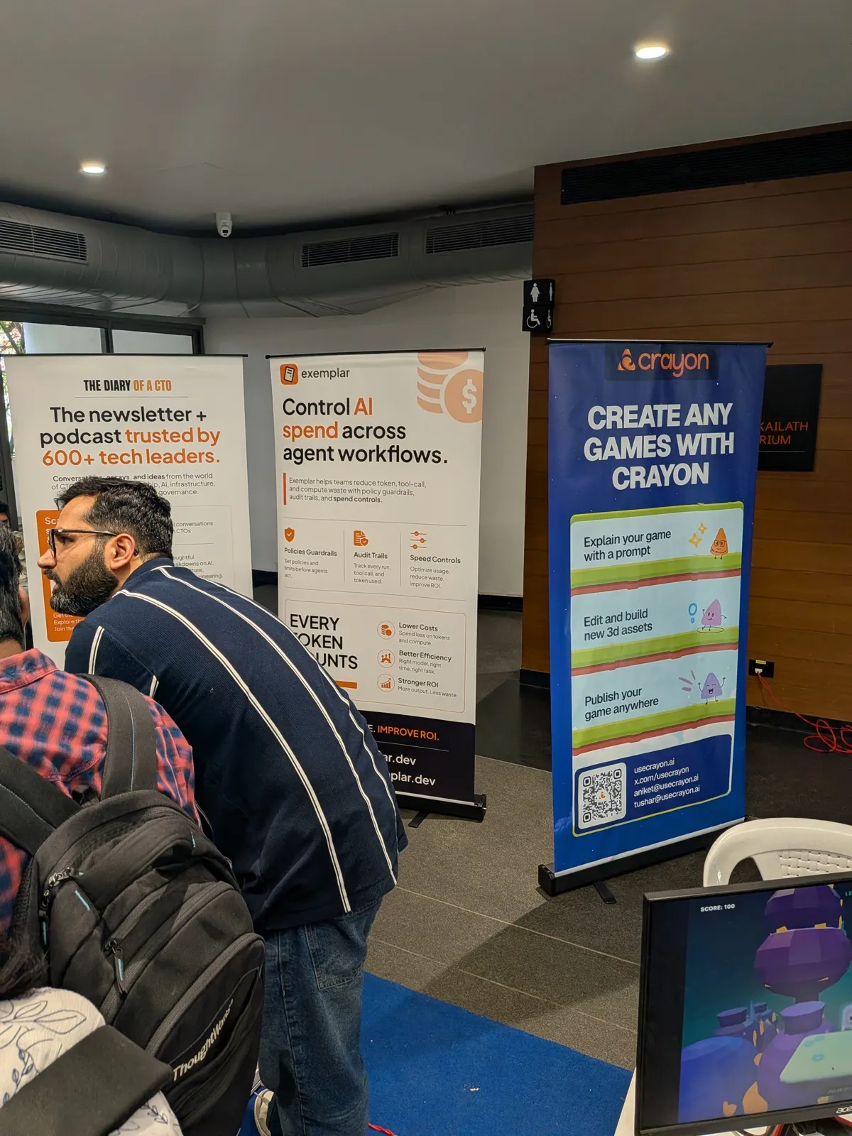 Booth banners at Agentic Summit: The Diary of a CTO, Exemplar, and Crayon, with a game demo running on a monitor