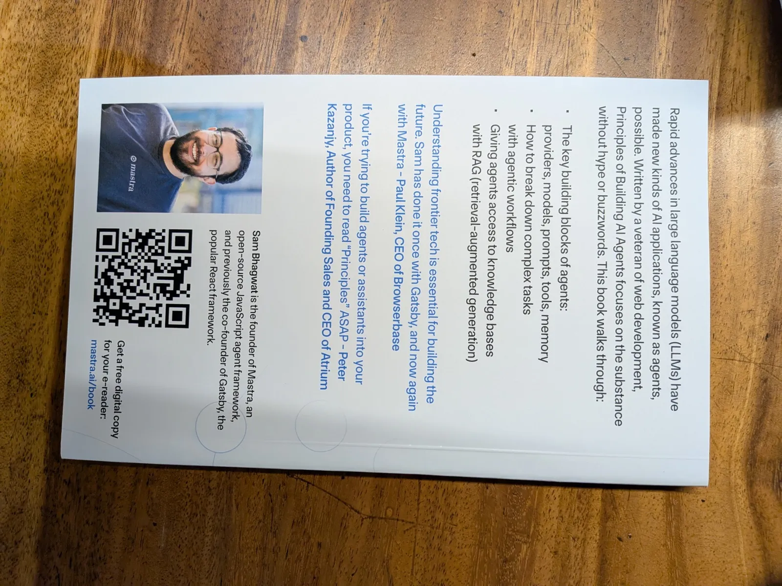 The back cover of “Principles of Building AI Agents” by Sam Bhagwat, sitting on a wooden table